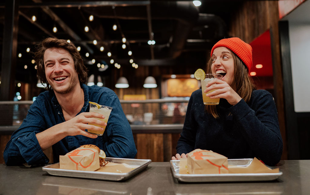 Woman laughing at man while both are holding drinks