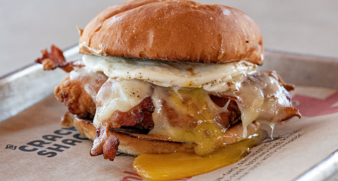 Image of sandwich with chicken, dripping fried egg, cheese, and bacon.