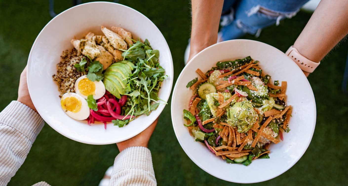 Image of two people holding salads in bowls